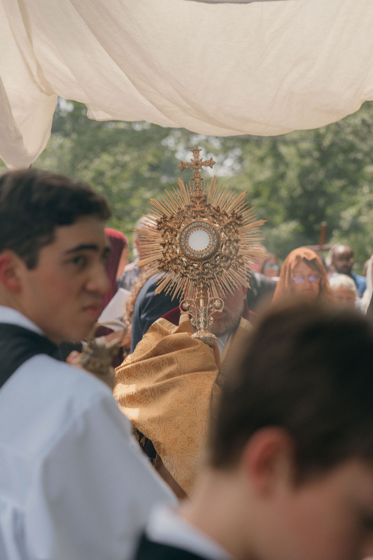 Altar server beside the priest carrying the monstrance in a Corpus Christi Eucharistic procession