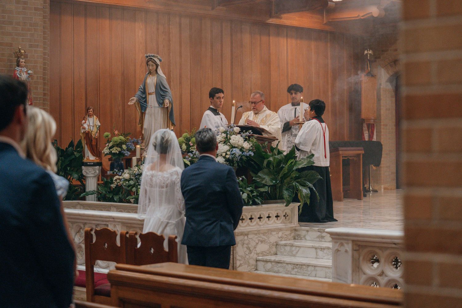 Bride and groom kneeling at the Marian shrine during the wedding