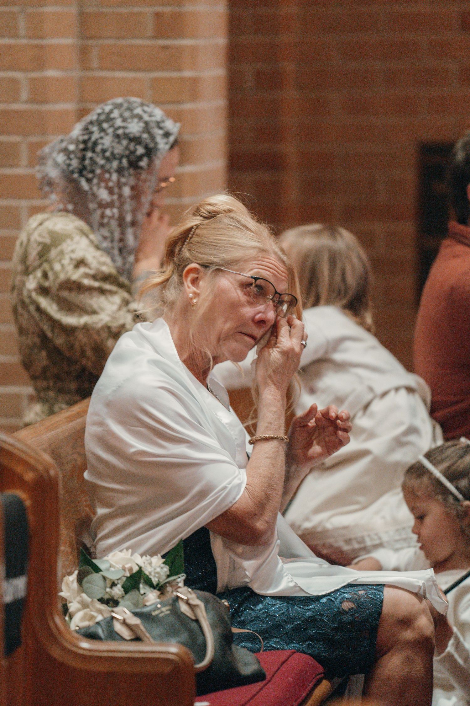 Wedding guest wiping away tears in the pews during the ceremony