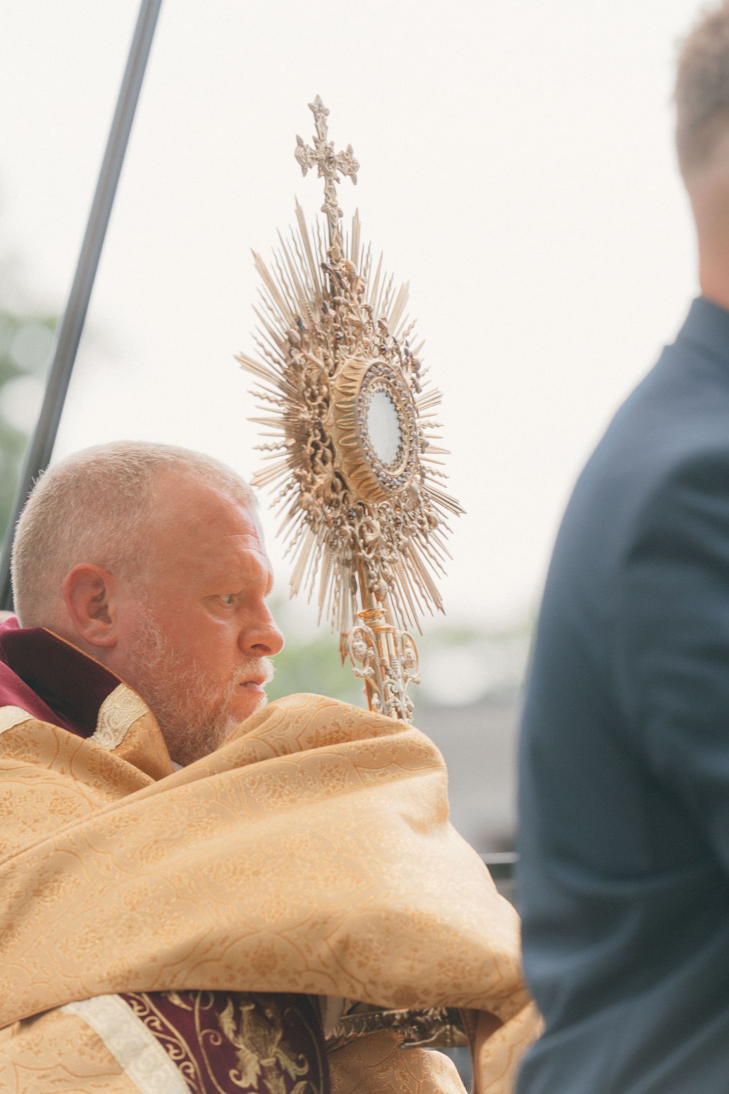 Close-up of a priest holding a gold monstrance during a Corpus Christi procession