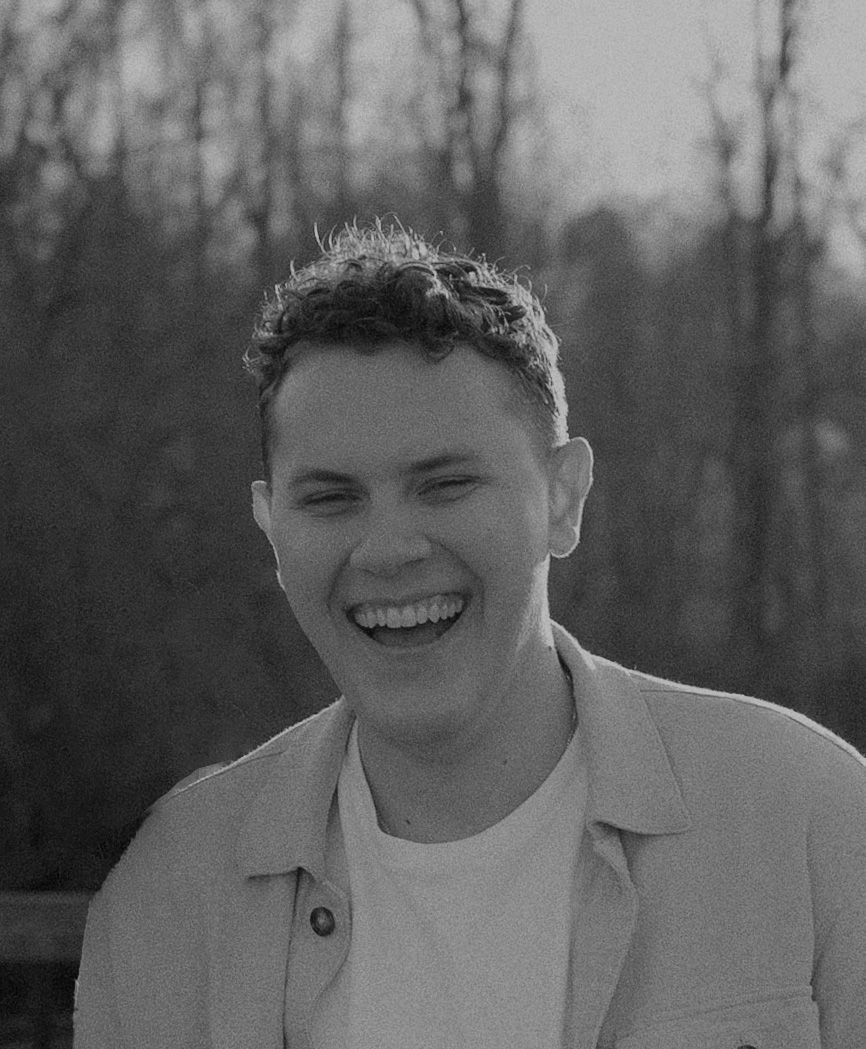 Black and white portrait of Alex Krasowski, Catholic wedding photographer in Greensboro, NC, smiling outdoors