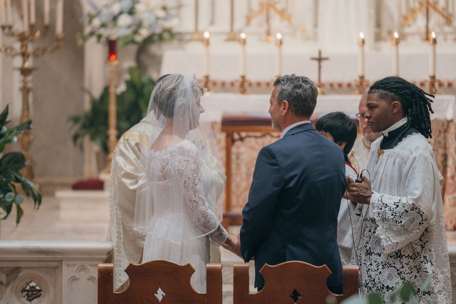 Bride and groom at the altar with a lector during the wedding liturgy