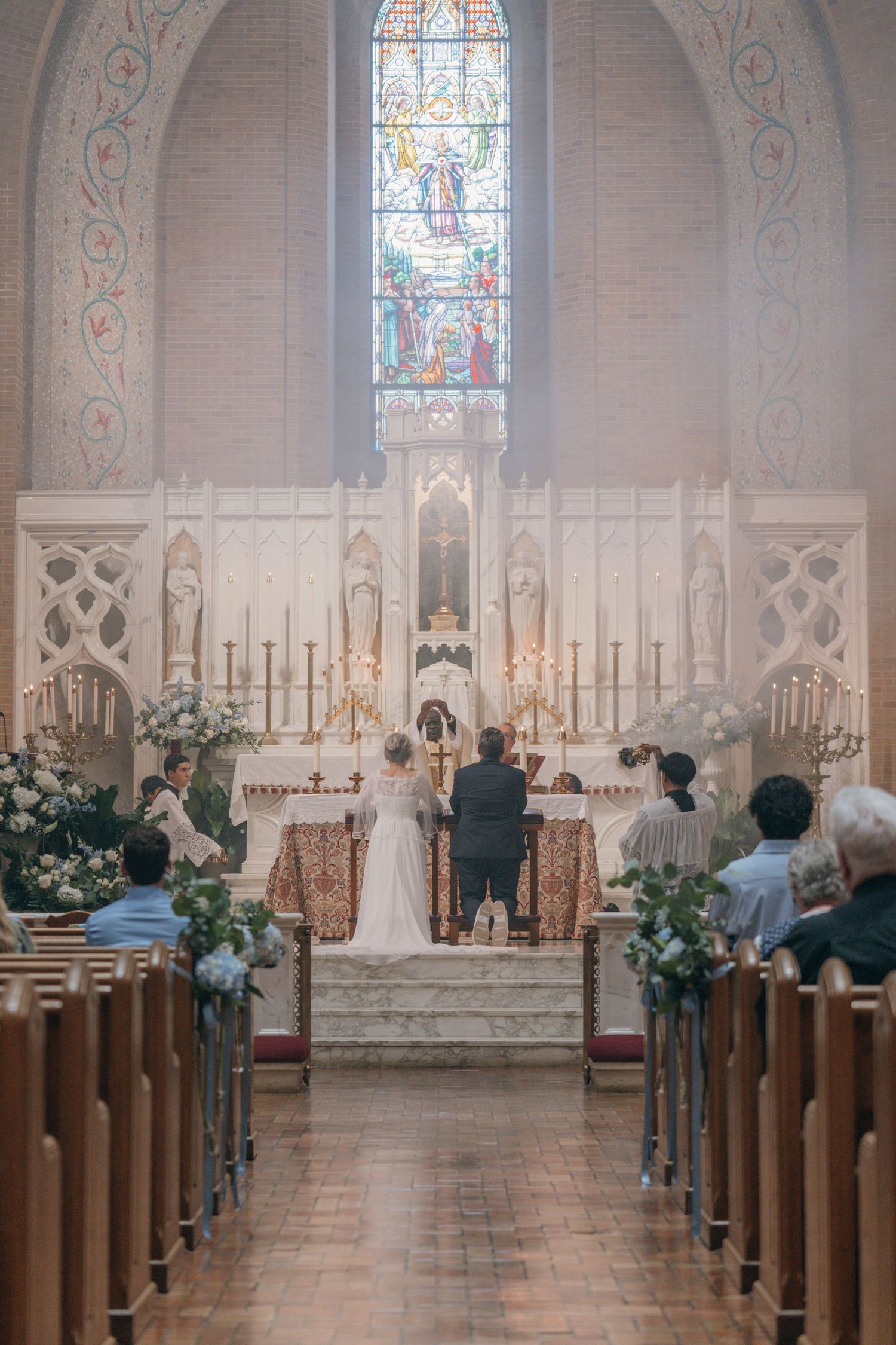 Bride and groom at the high altar of a church decorated with white flowers