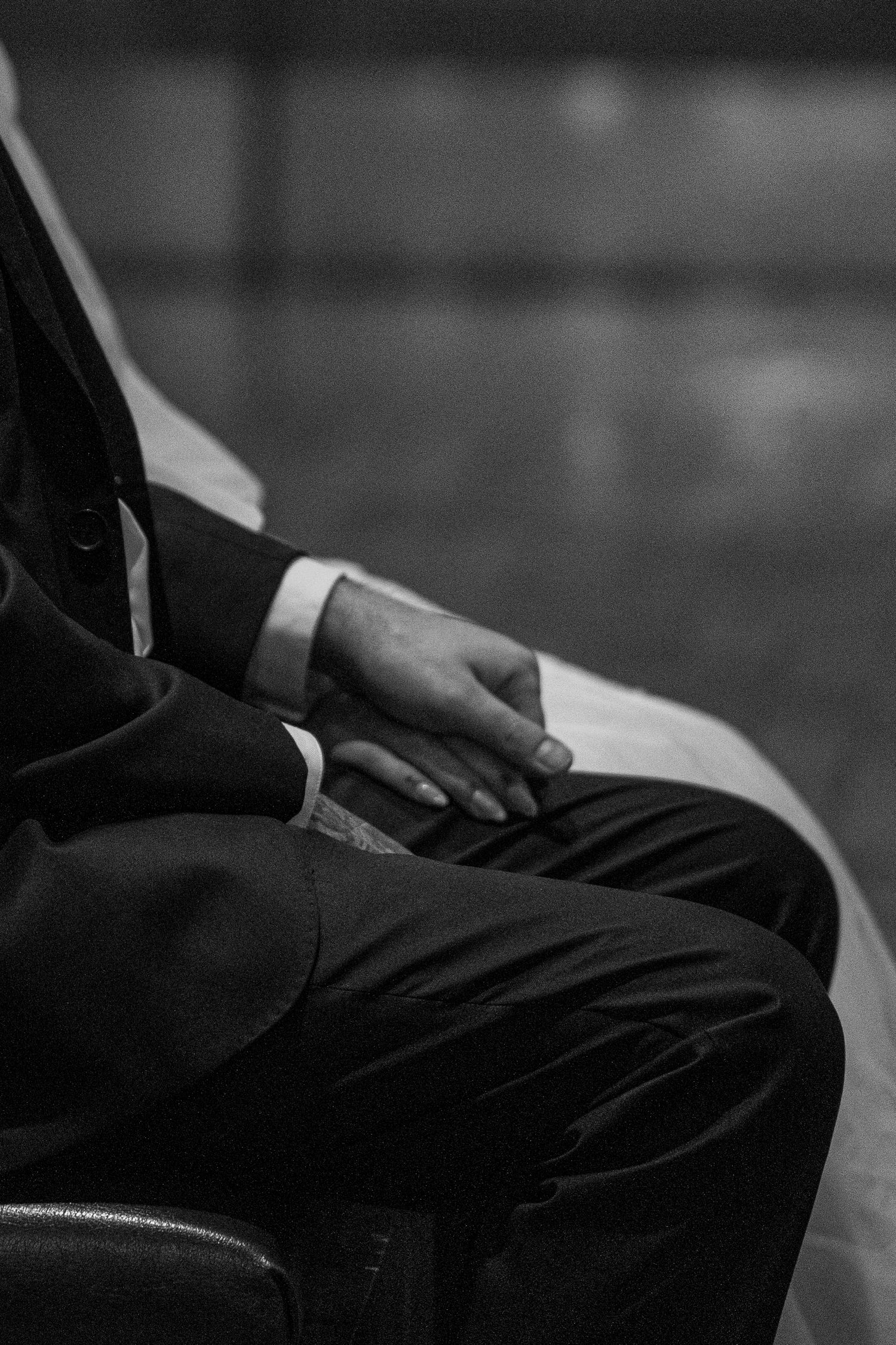 Black and white close-up of the groom's hands folded in prayer during Mass