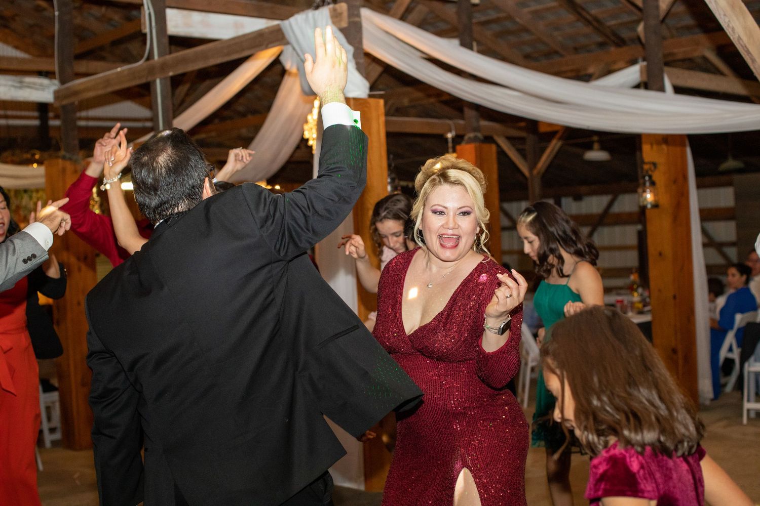 Wedding guest in a red velvet dress dancing with friends at the reception