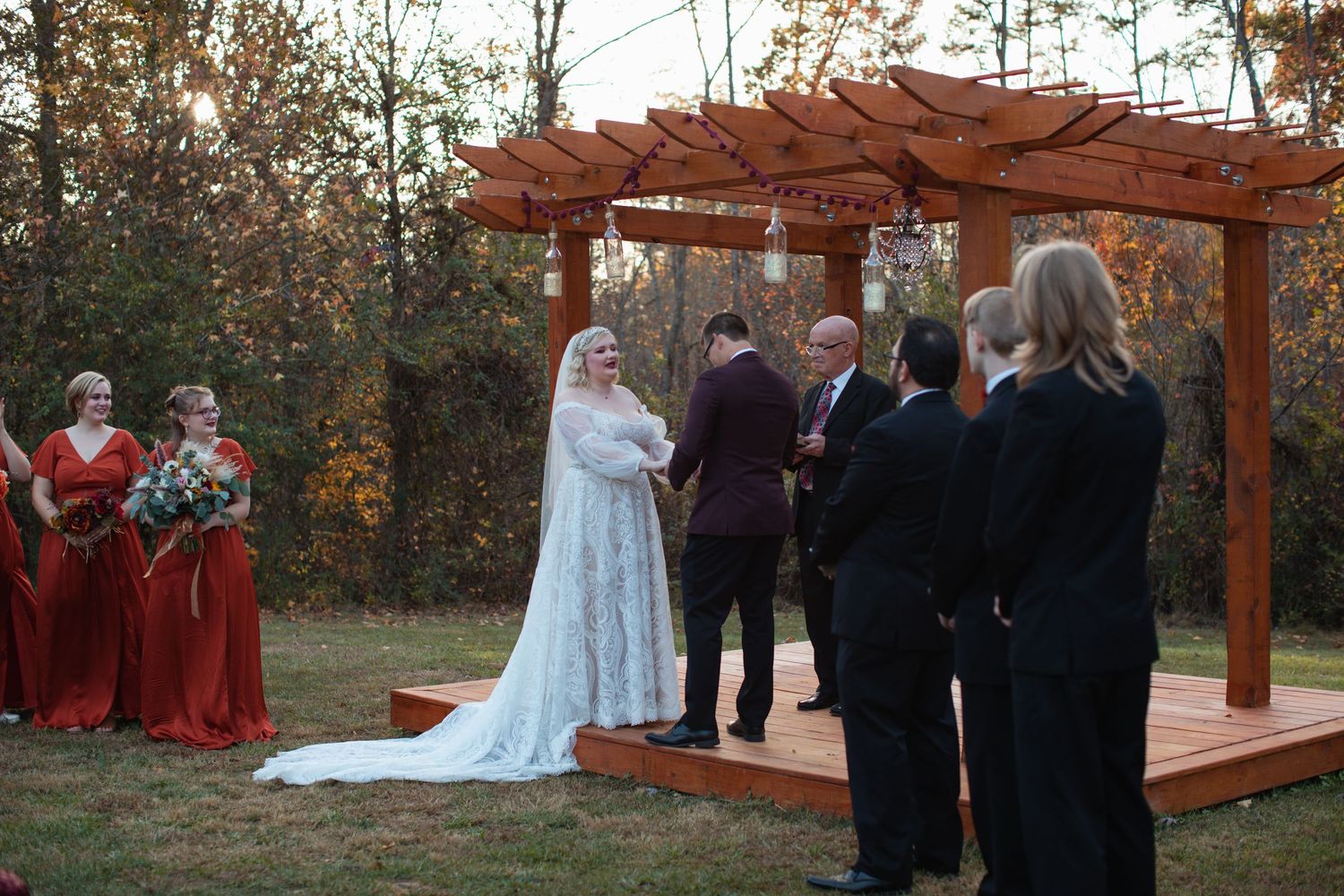 Bride and groom at the altar with bridesmaids in burgundy dresses