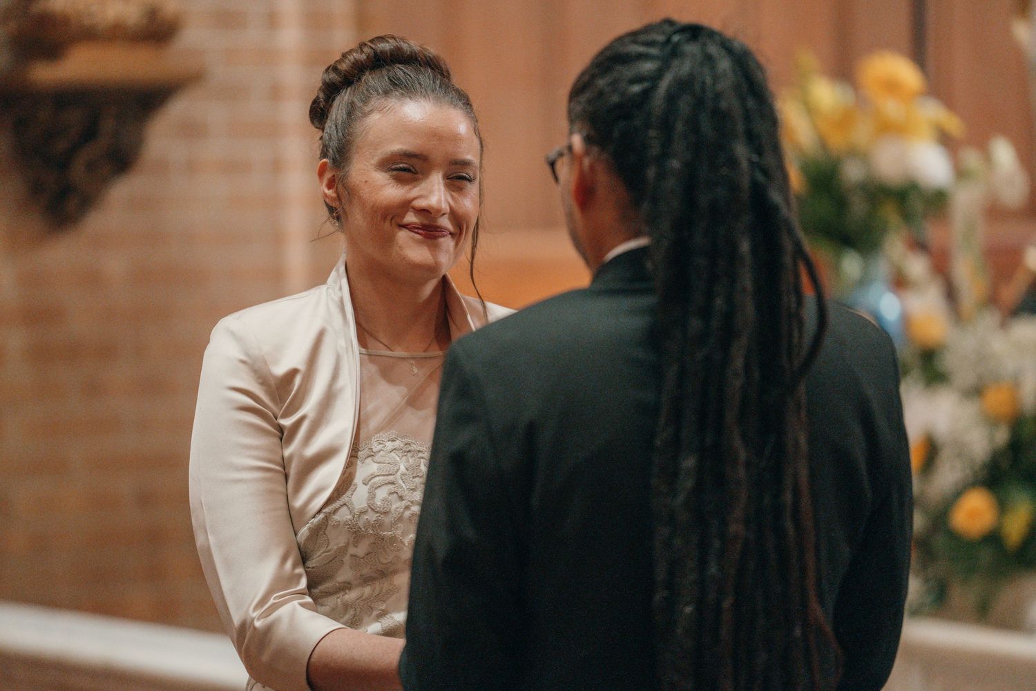 Bride smiling at the groom as they exchange vows in a church