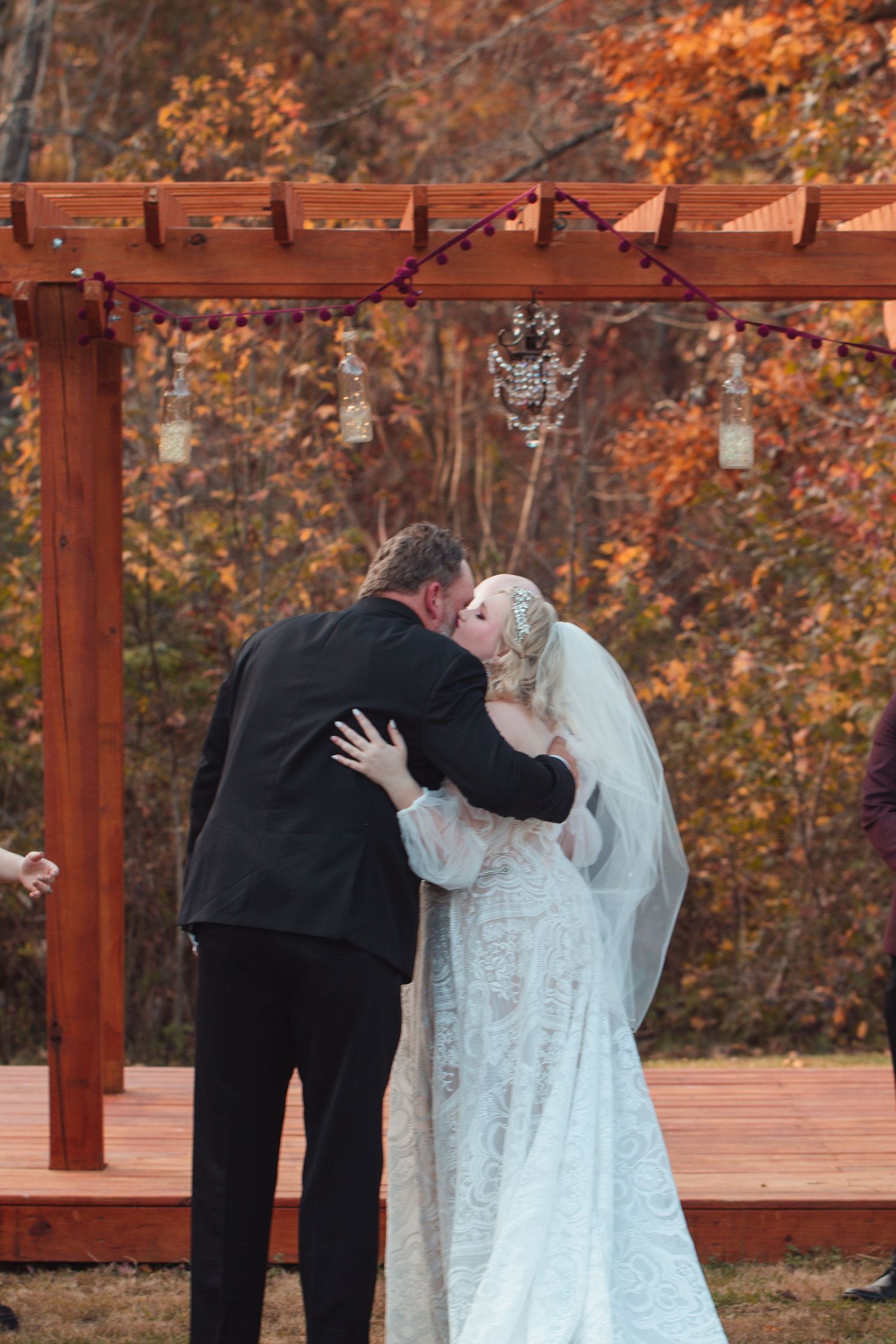 Newlyweds embracing under the pergola after their vows
