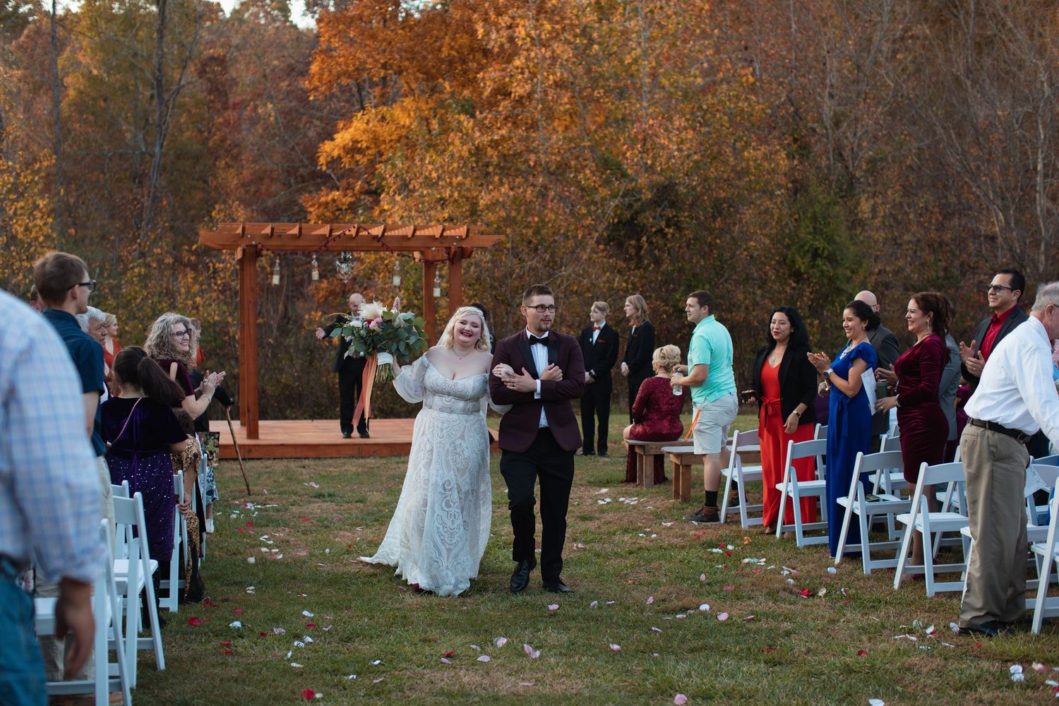Guests standing as the bride walks the aisle at an outdoor fall wedding