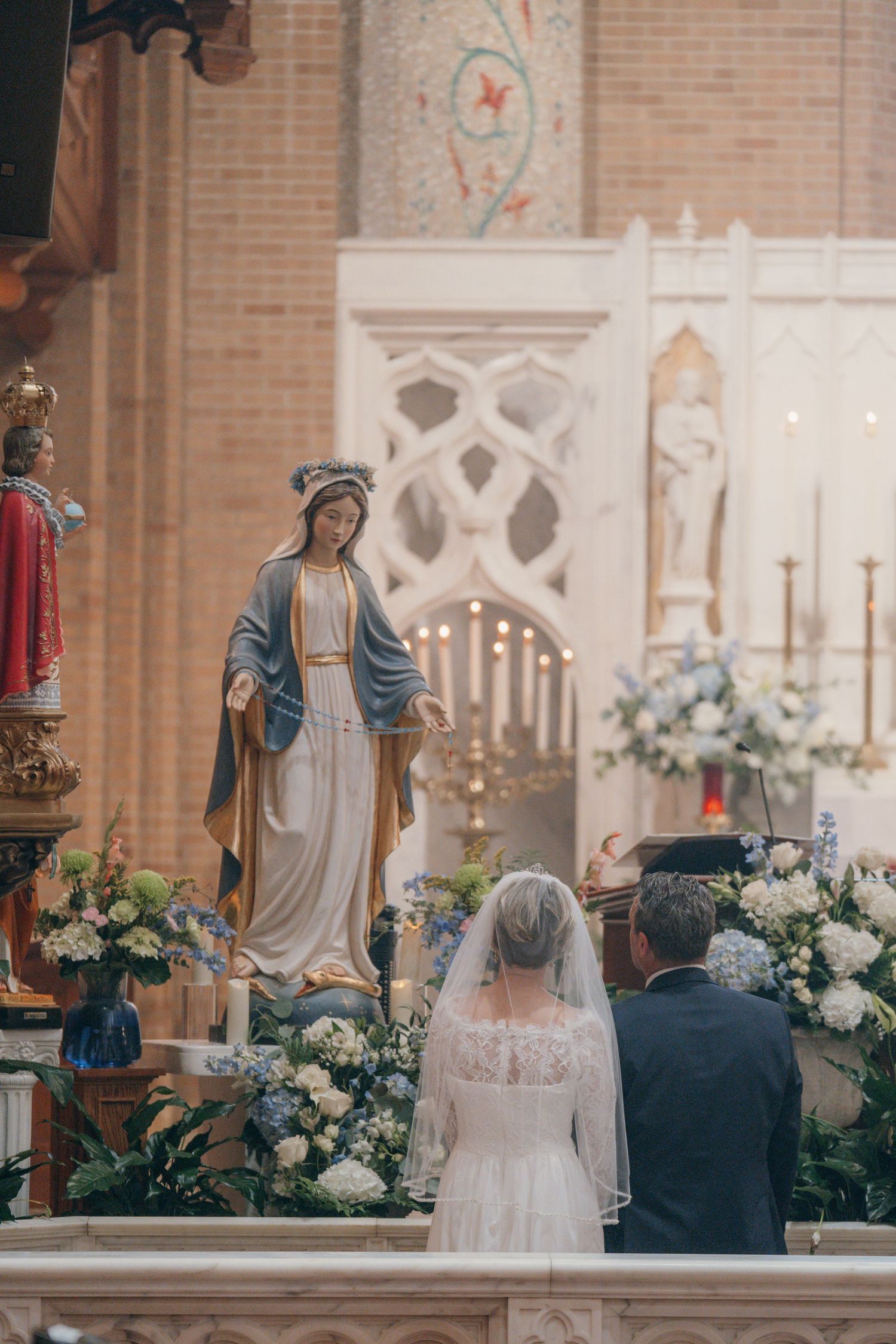 Bride and groom kneeling at the Marian altar during their Nuptial Mass