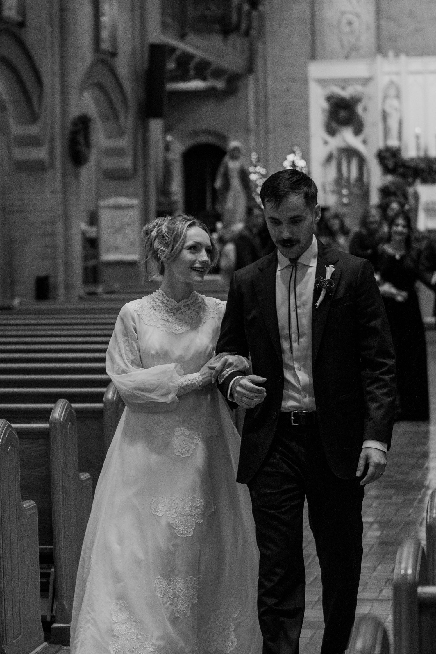 Black and white photo of the newlyweds recessing down the church aisle