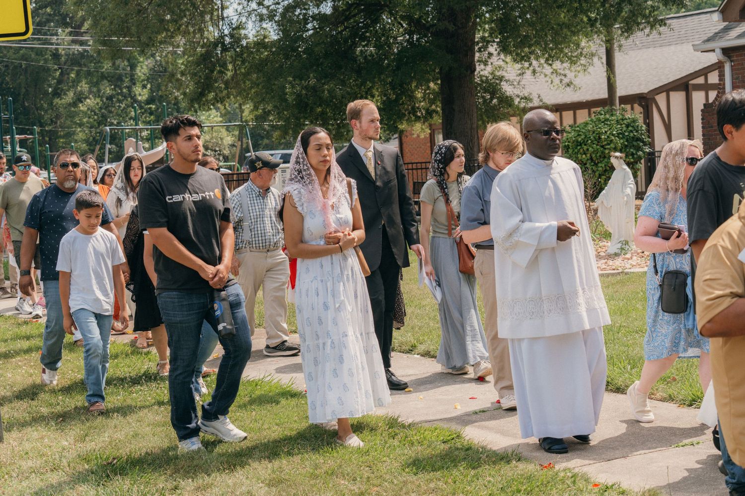 Families, altar servers and a priest walking together in a Corpus Christi Eucharistic procession