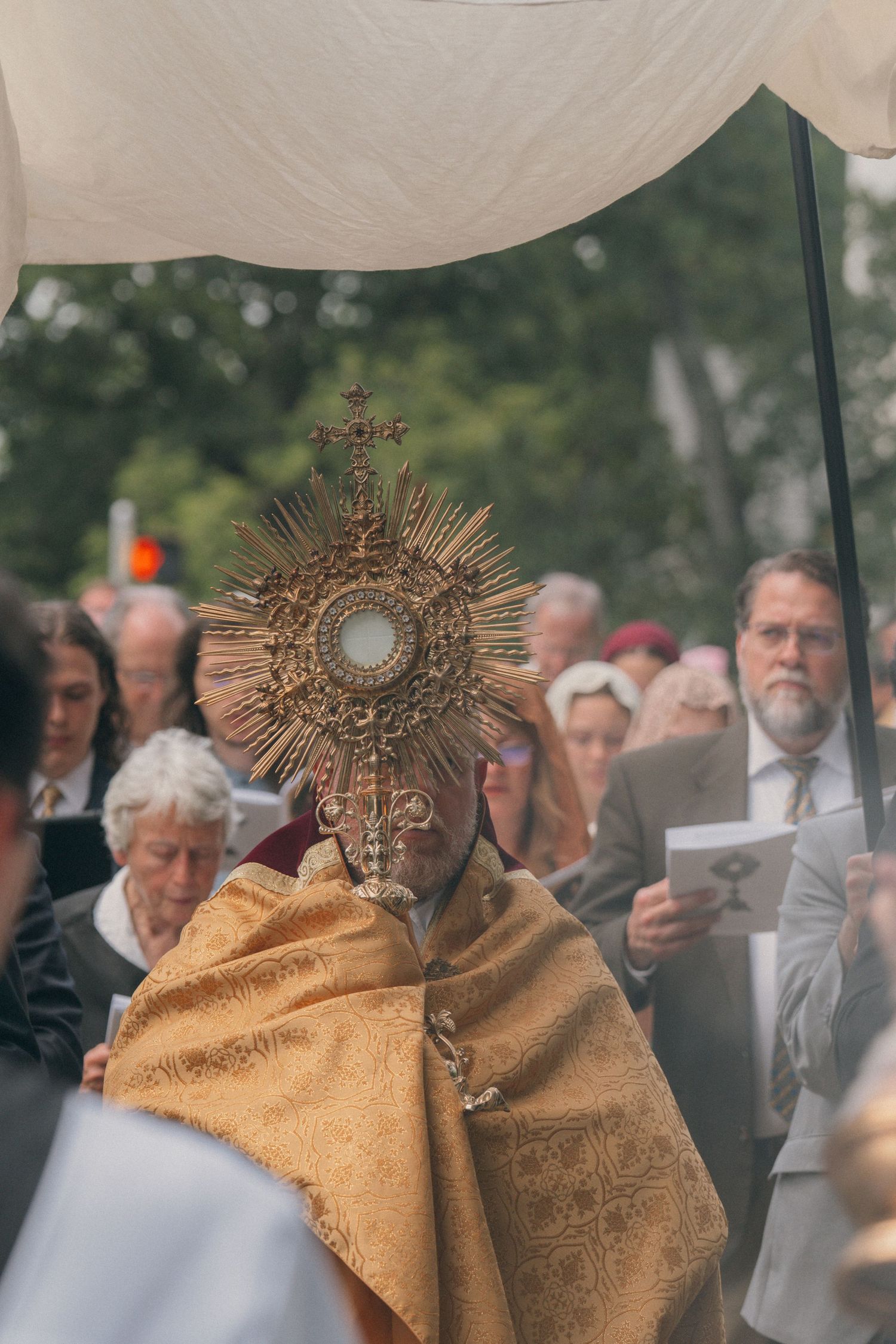 Parishioners pressing close to see the monstrance during an outdoor Corpus Christi procession