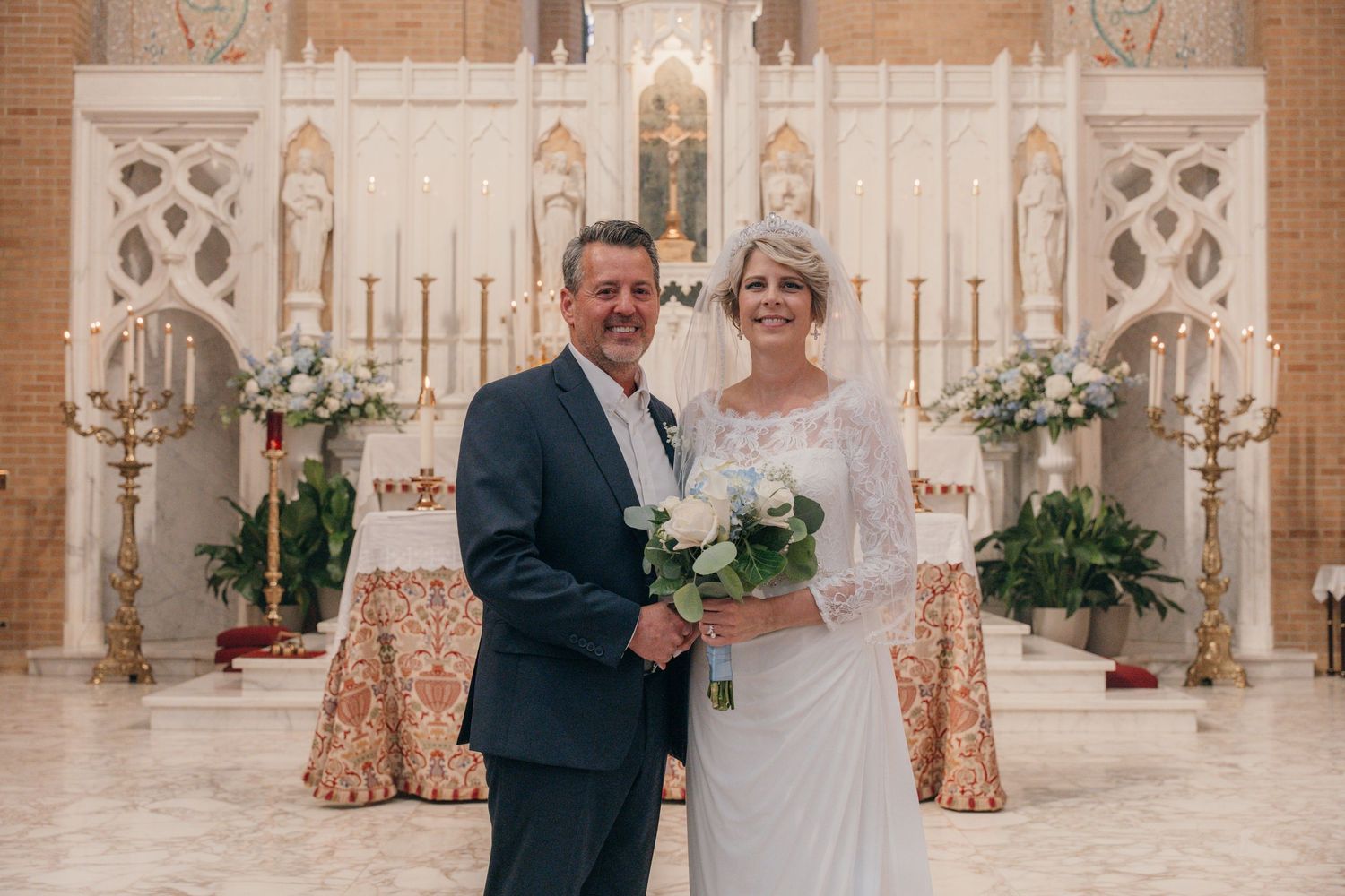 Bride and groom smiling at the altar of a Catholic church after their wedding Mass