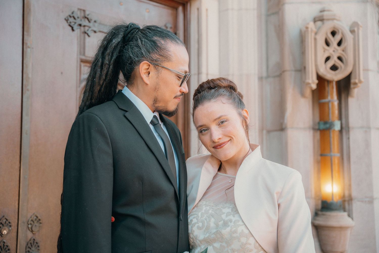 Groom and bride laughing together in the church doorway