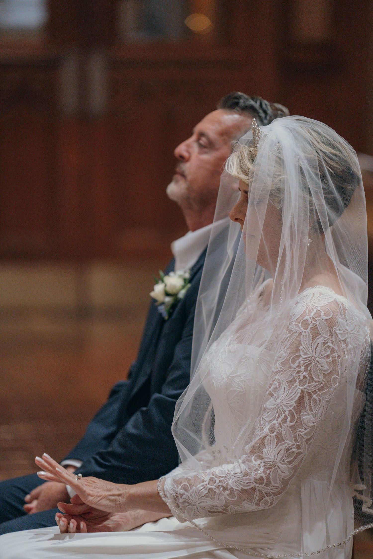 Bride and groom seated together in prayer during their wedding Mass