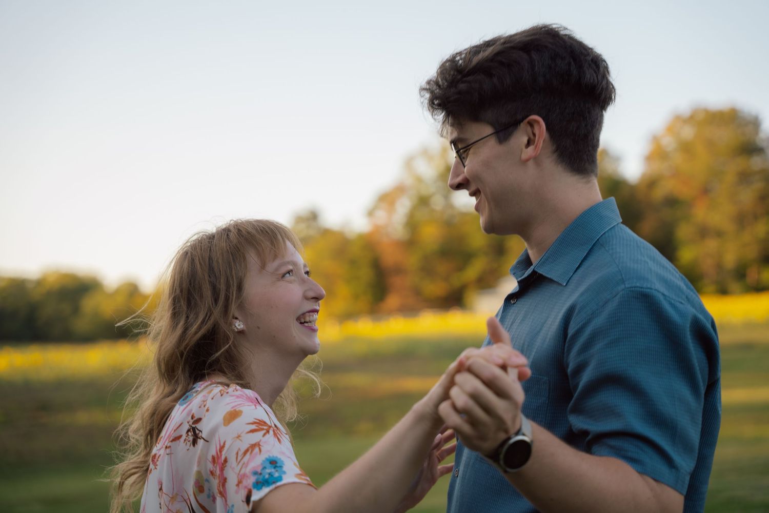 Couple holding hands and dancing in a meadow at sunset