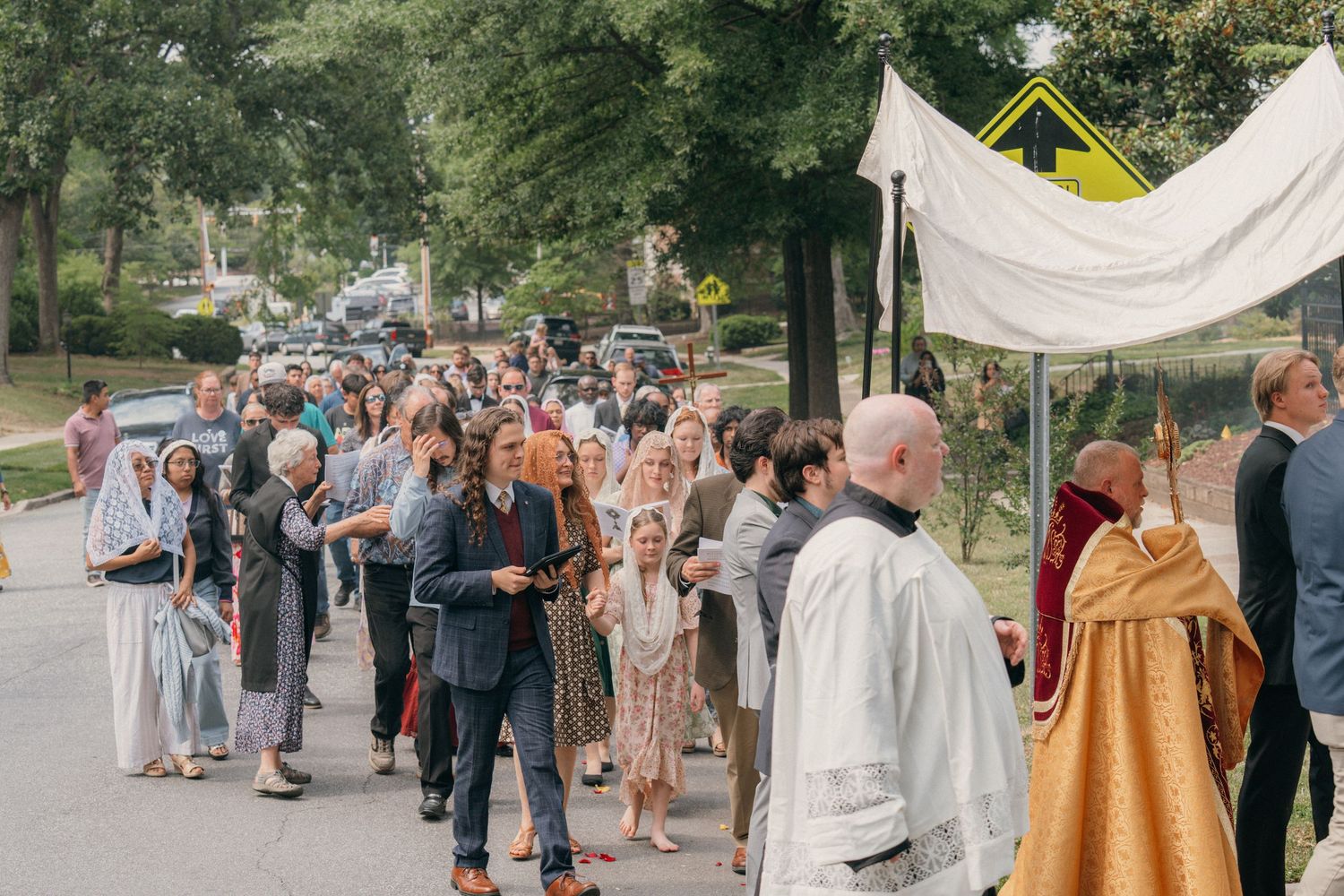 Long line of parishioners following the canopy down a residential street on Corpus Christi