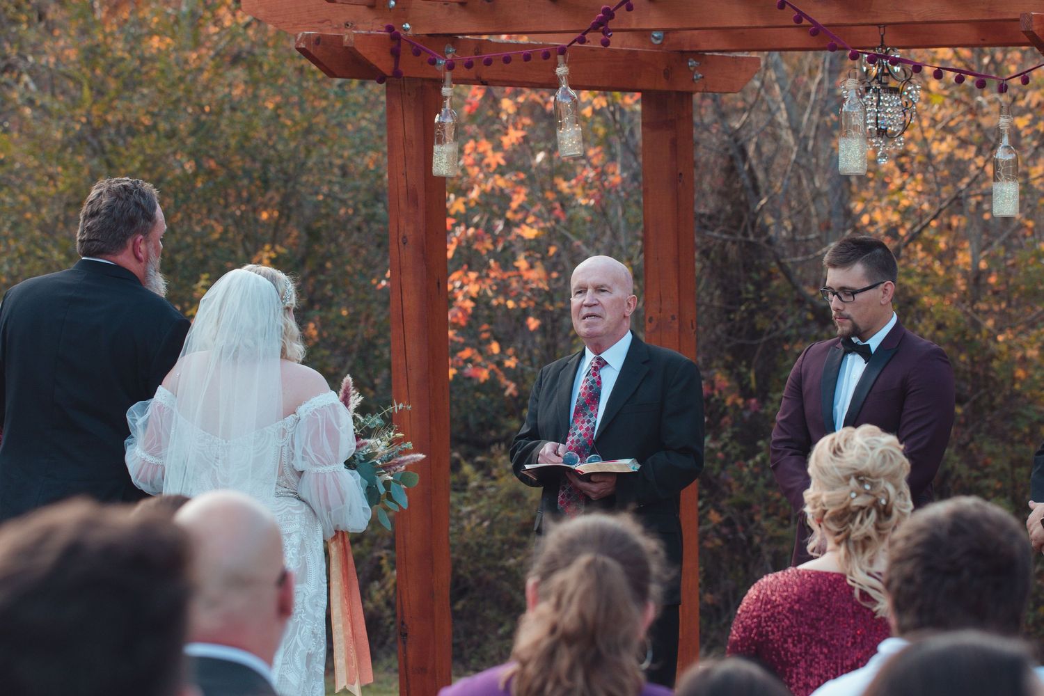 Guests watching the bride and groom at the altar of an outdoor fall wedding