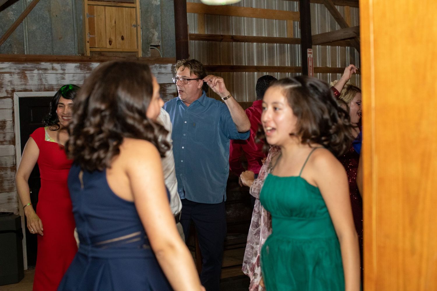 Wedding guests in colorful dresses dancing at a barn reception