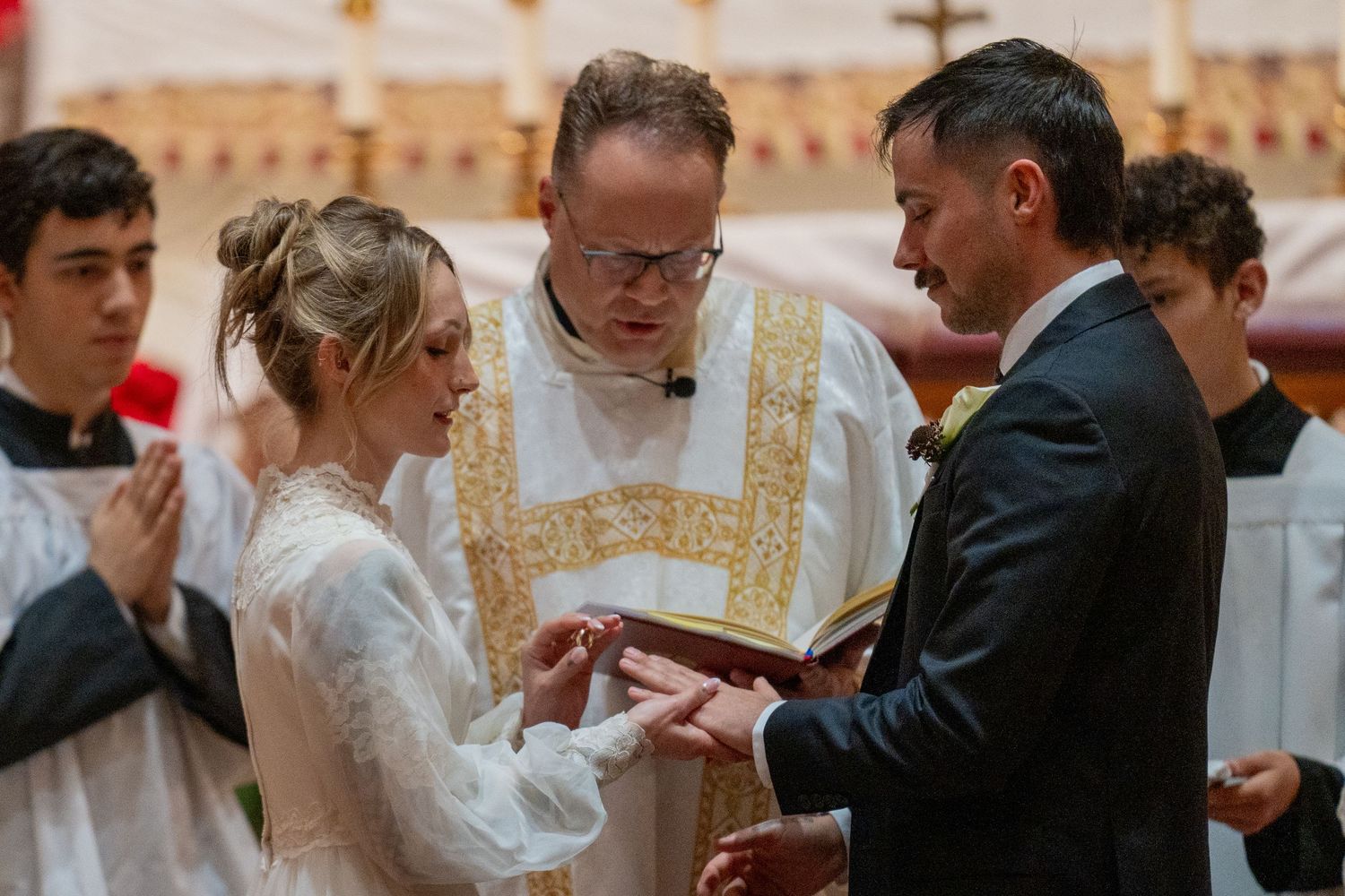 Bride and groom exchanging rings before the priest and altar servers