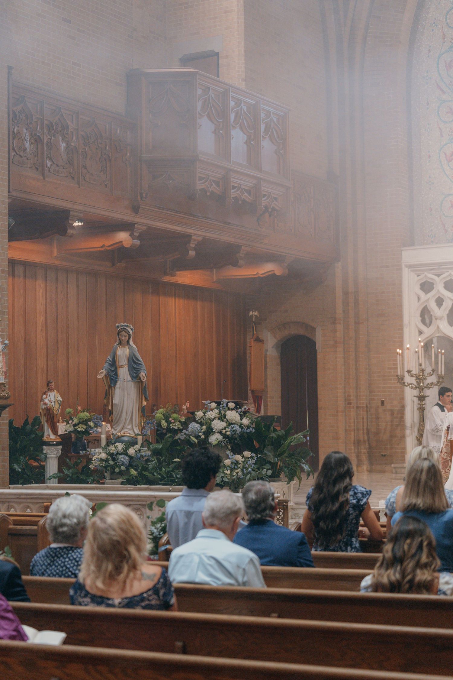 Guests in the pews as incense fills the church during the wedding Mass