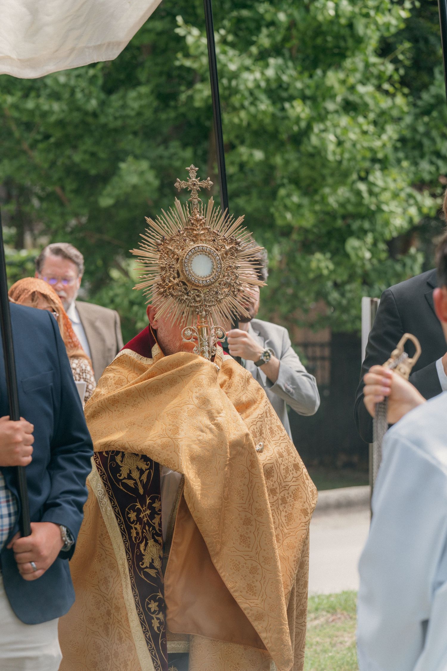 Priest raising the monstrance as parishioners follow in a Corpus Christi procession