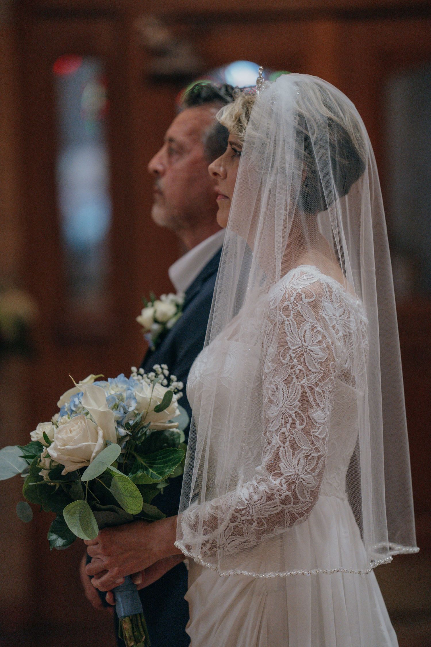 Bride holding a white and blue bouquet with her father before walking the aisle