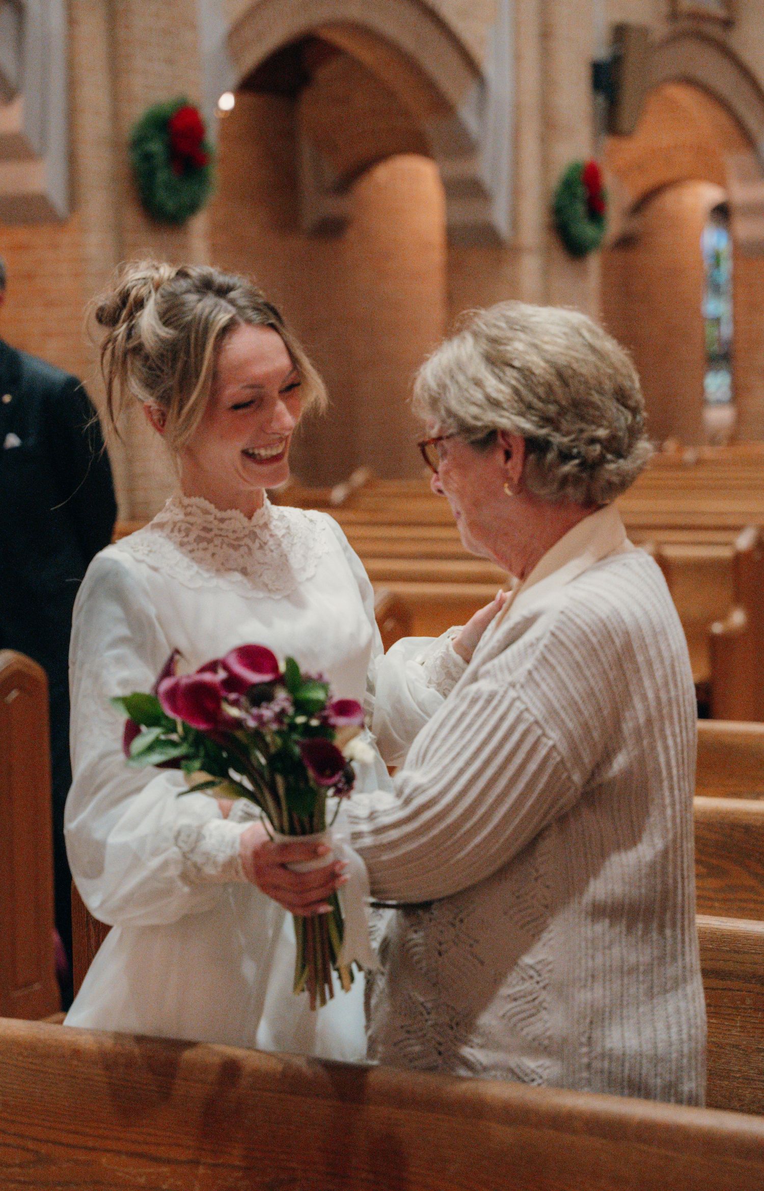 Bride holding red roses and greeting a loved one in church