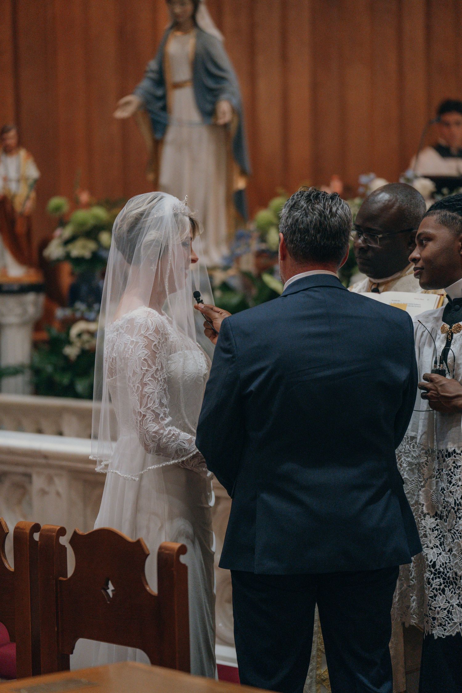 Bride and groom at the altar beneath a statue of Mary