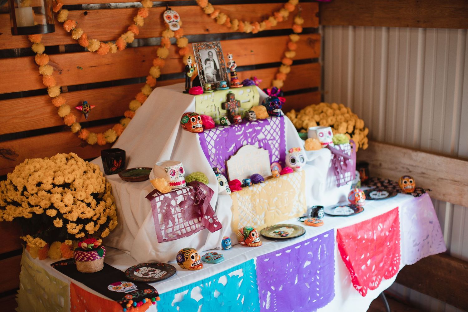 Colorful memorial altar with papel picado and photos honoring loved ones at a wedding