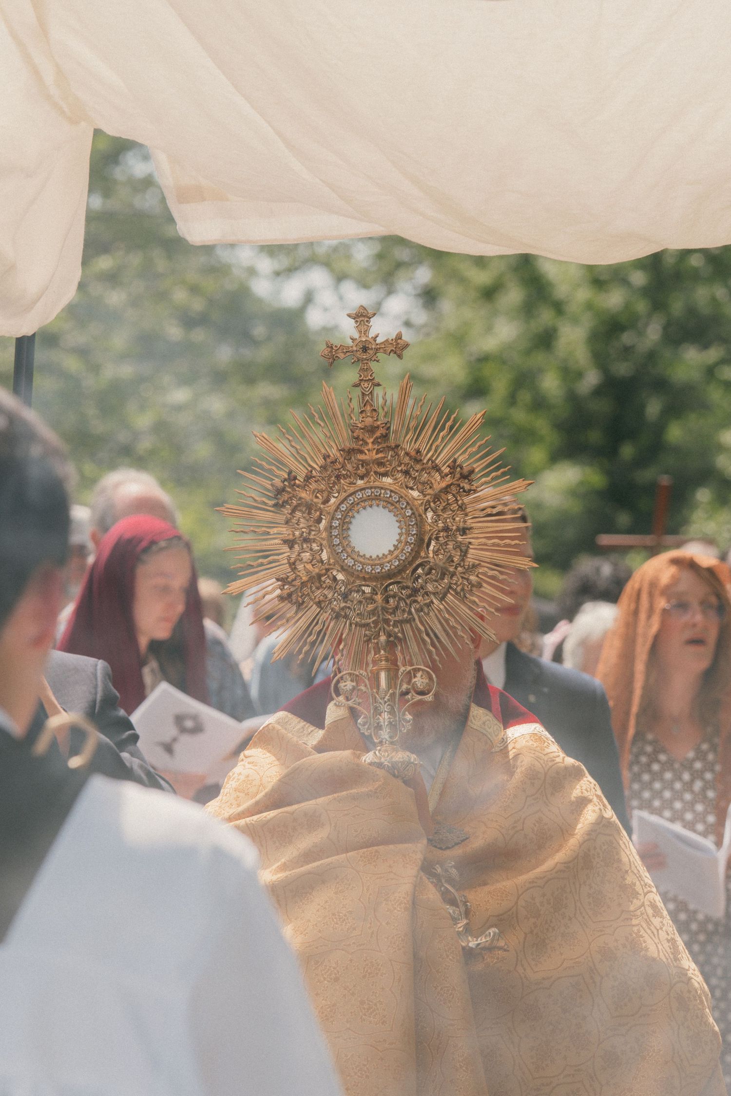 Incense smoke rising around the priest and monstrance during a Corpus Christi procession