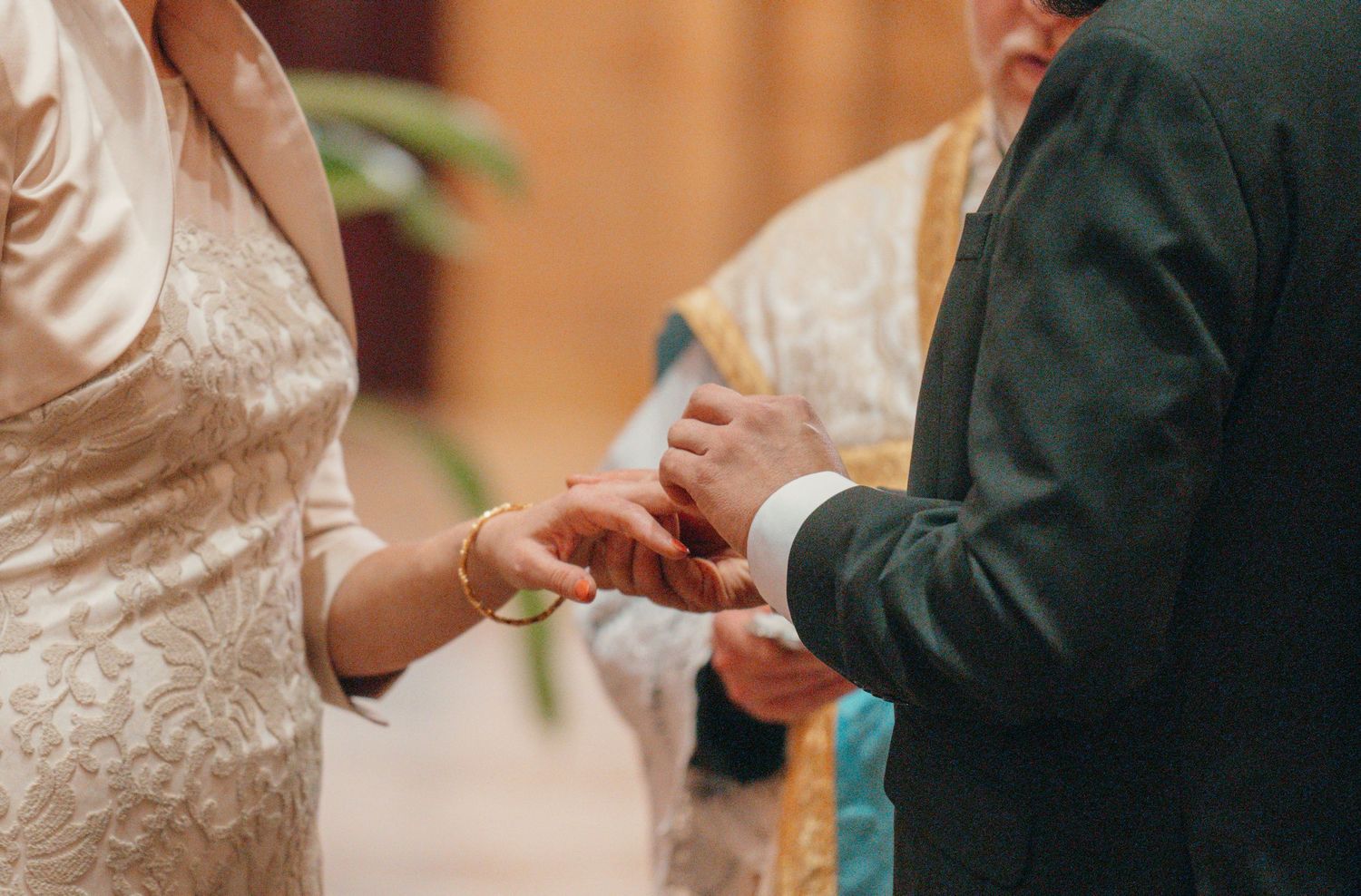 Close-up of the bride placing a wedding ring on the groom's finger