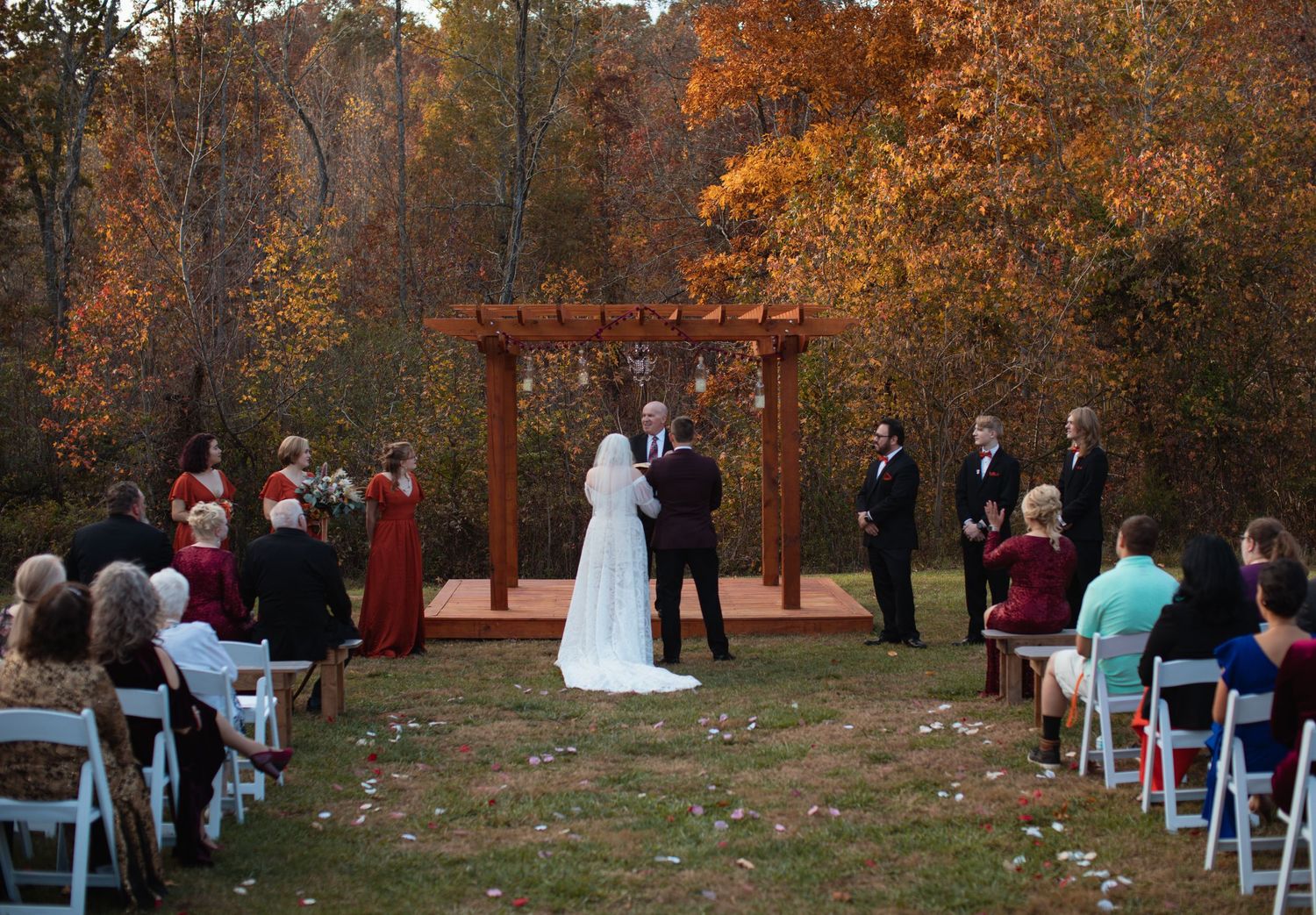 Outdoor wedding ceremony framed by orange autumn leaves