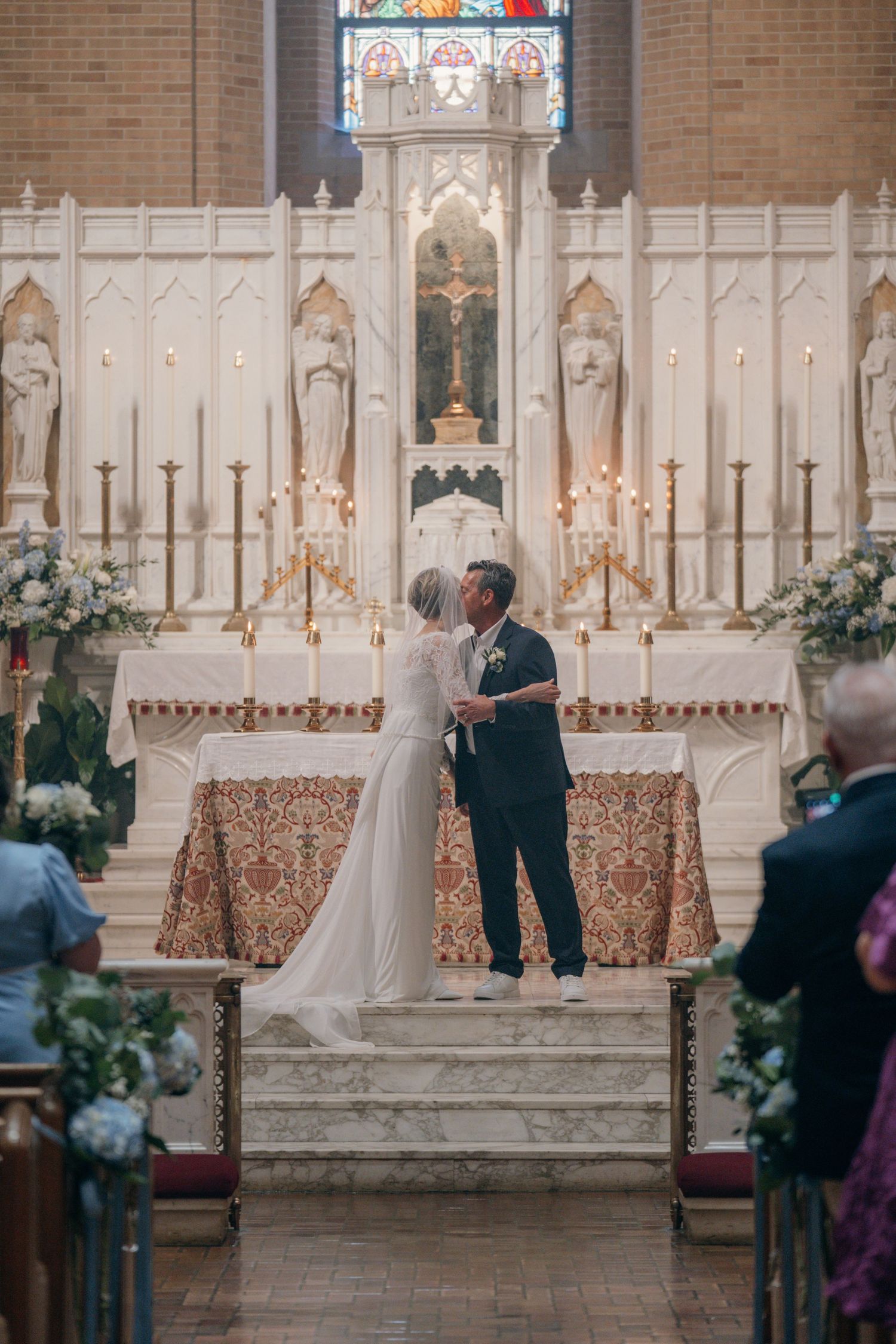Bride and groom sharing their first kiss before a Gothic high altar