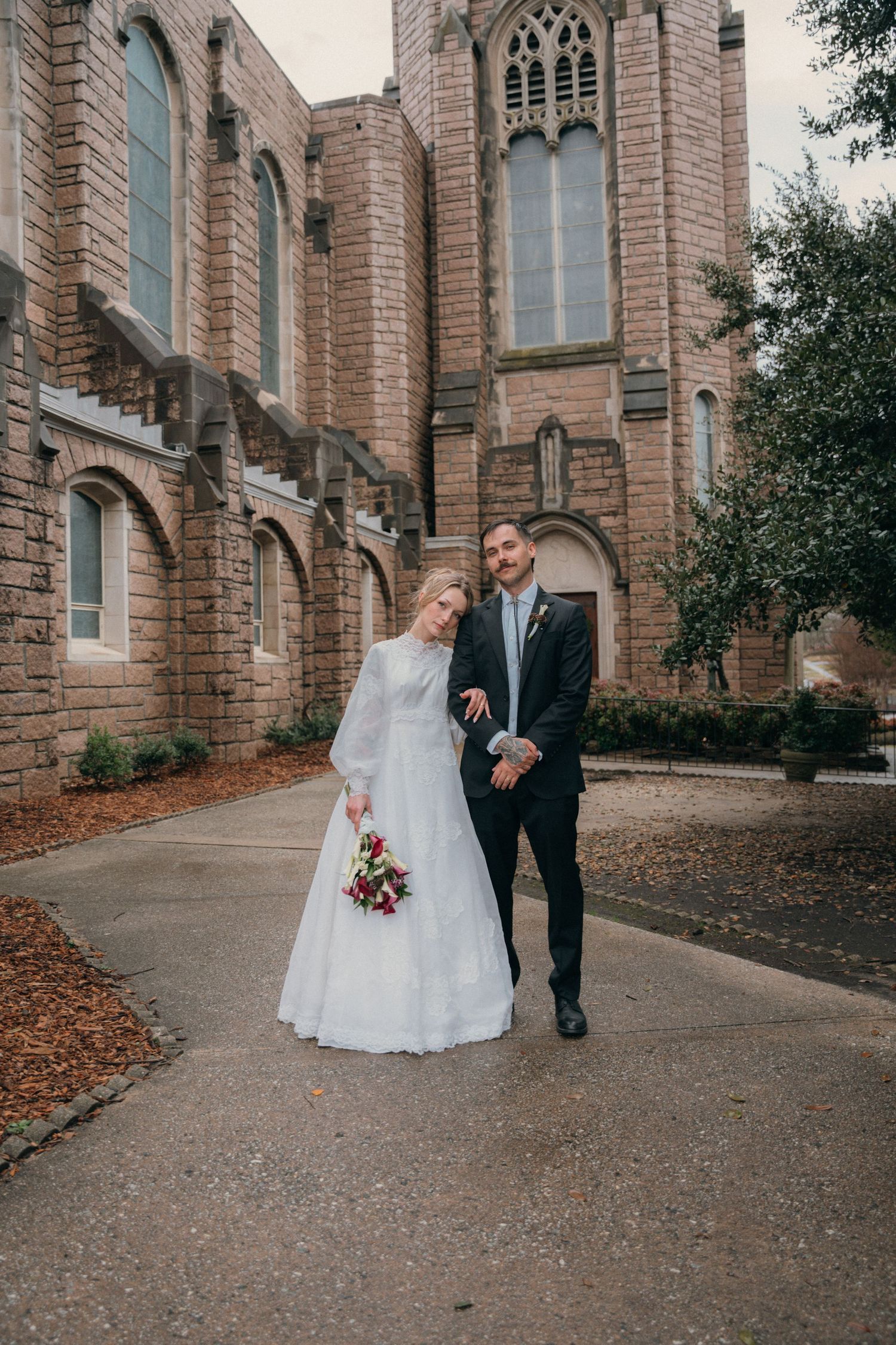 Bride and groom walking together outside a Gothic brick church