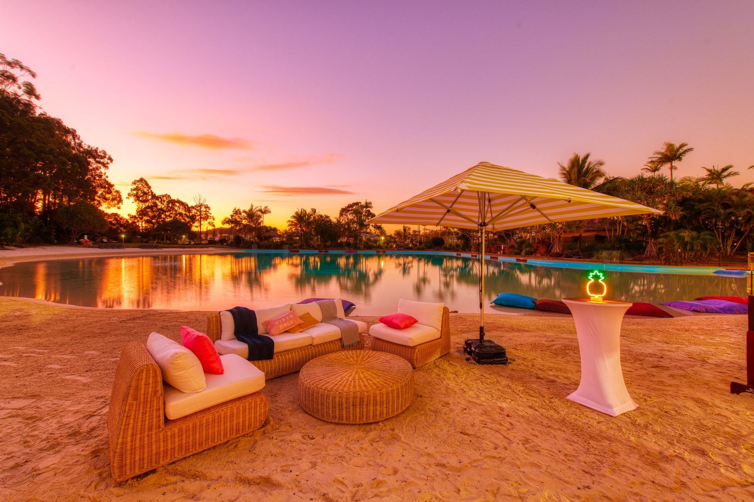 Luxurious poolside lounge area with wicker furniture at stunning tropical sunset.