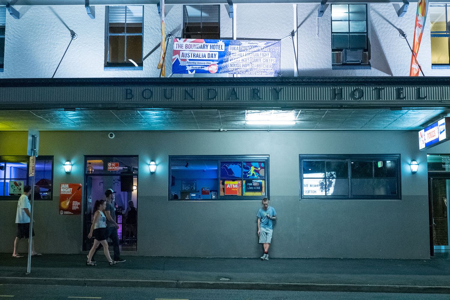 Color night photo of the Boundary Hotel facade with neon lights and pedestrians on the sidewalk.