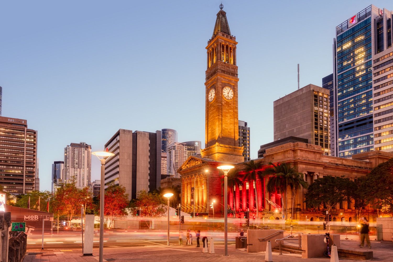 Brisbane City Hall clock tower and surrounding CBD skyline photographed at twilight with light trails on the street.