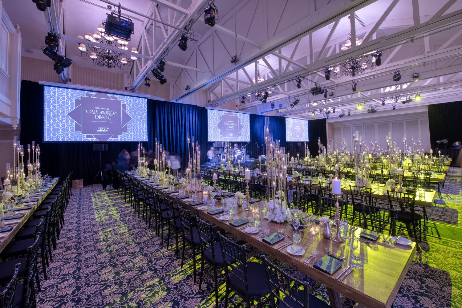 Spacious event venue with long dining tables and decorative centerpieces under industrial ceiling.