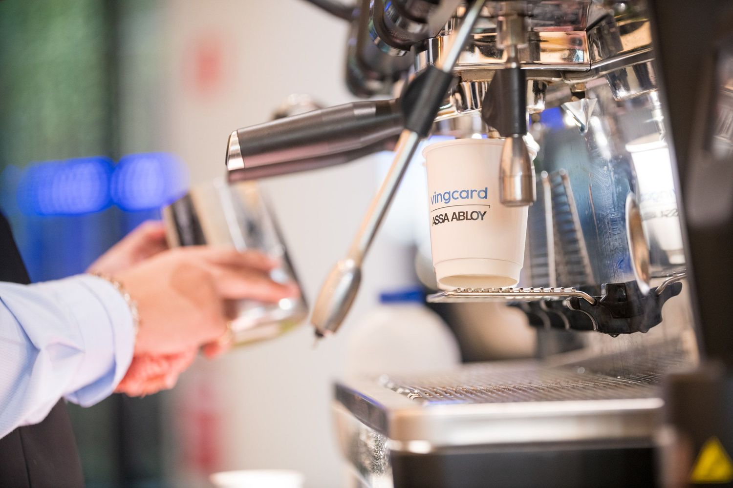 Barista operates professional espresso machine with branded Uracana Stanboy coffee cup closeup.