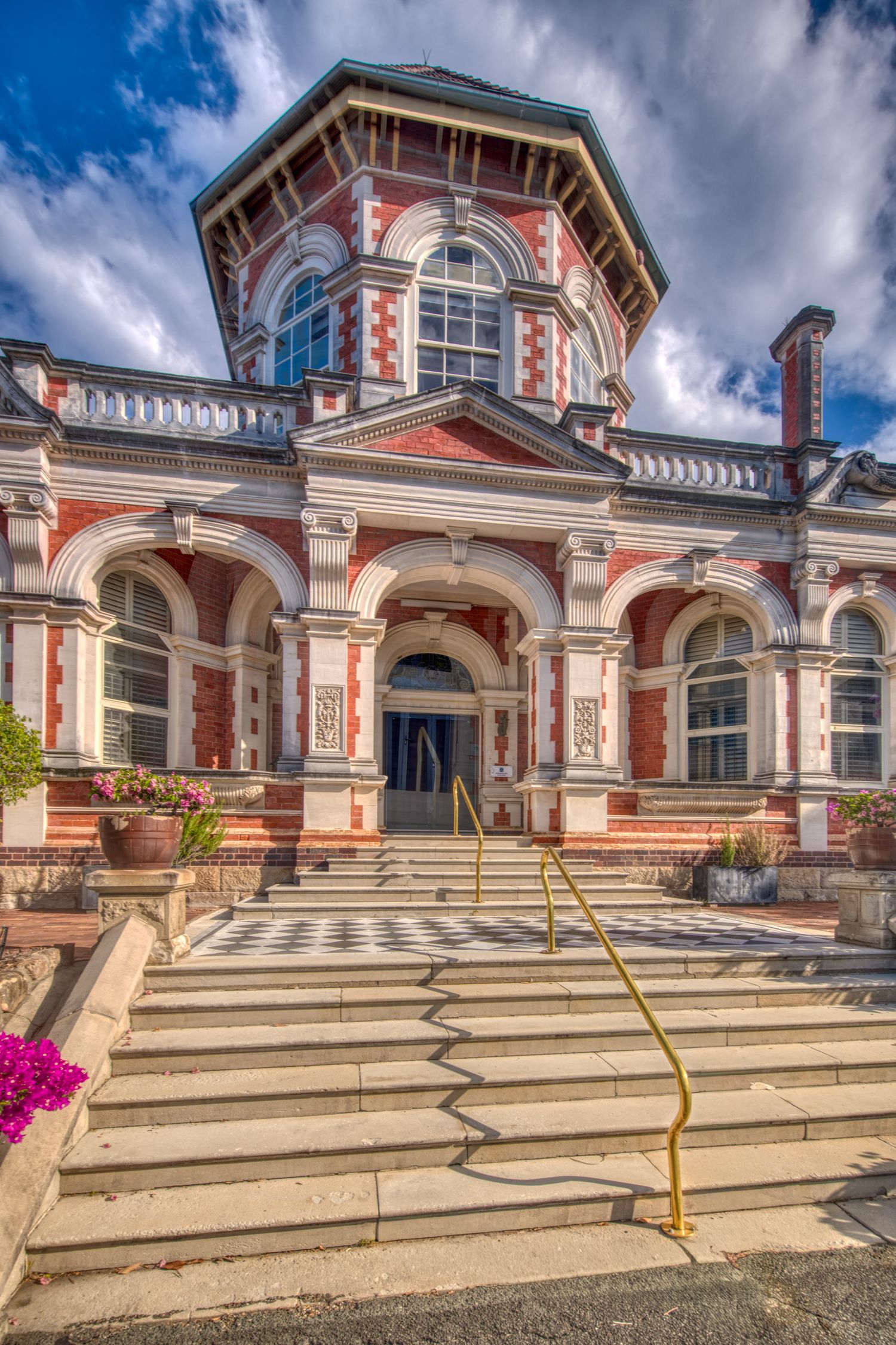 Historic red brick building with ornate tower and checkered entrance steps.