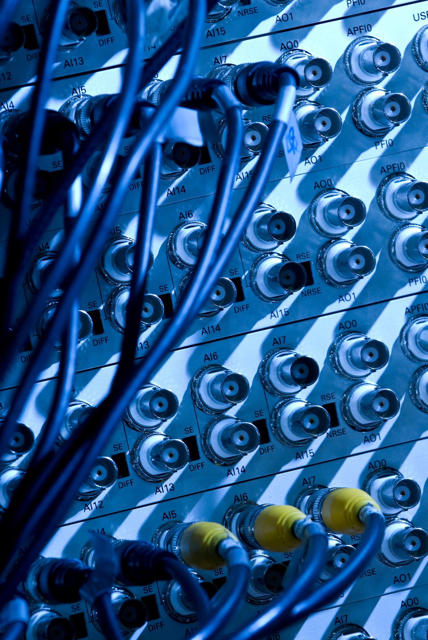 Close-up of blue-tinted audio mixing panel with BNC connectors and cables.