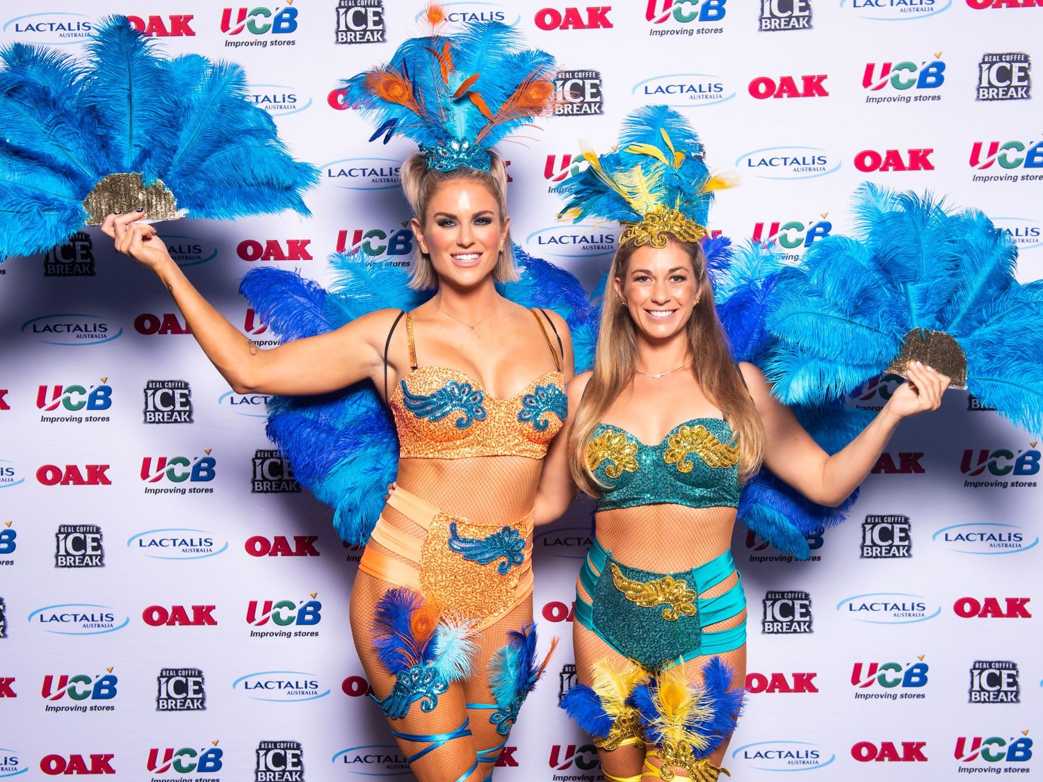 Two women in blue carnival costumes with feathered fans.