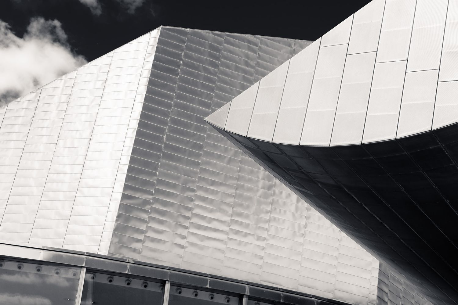 Black and white close-up of a modern building with angular geometric metallic facade panels.