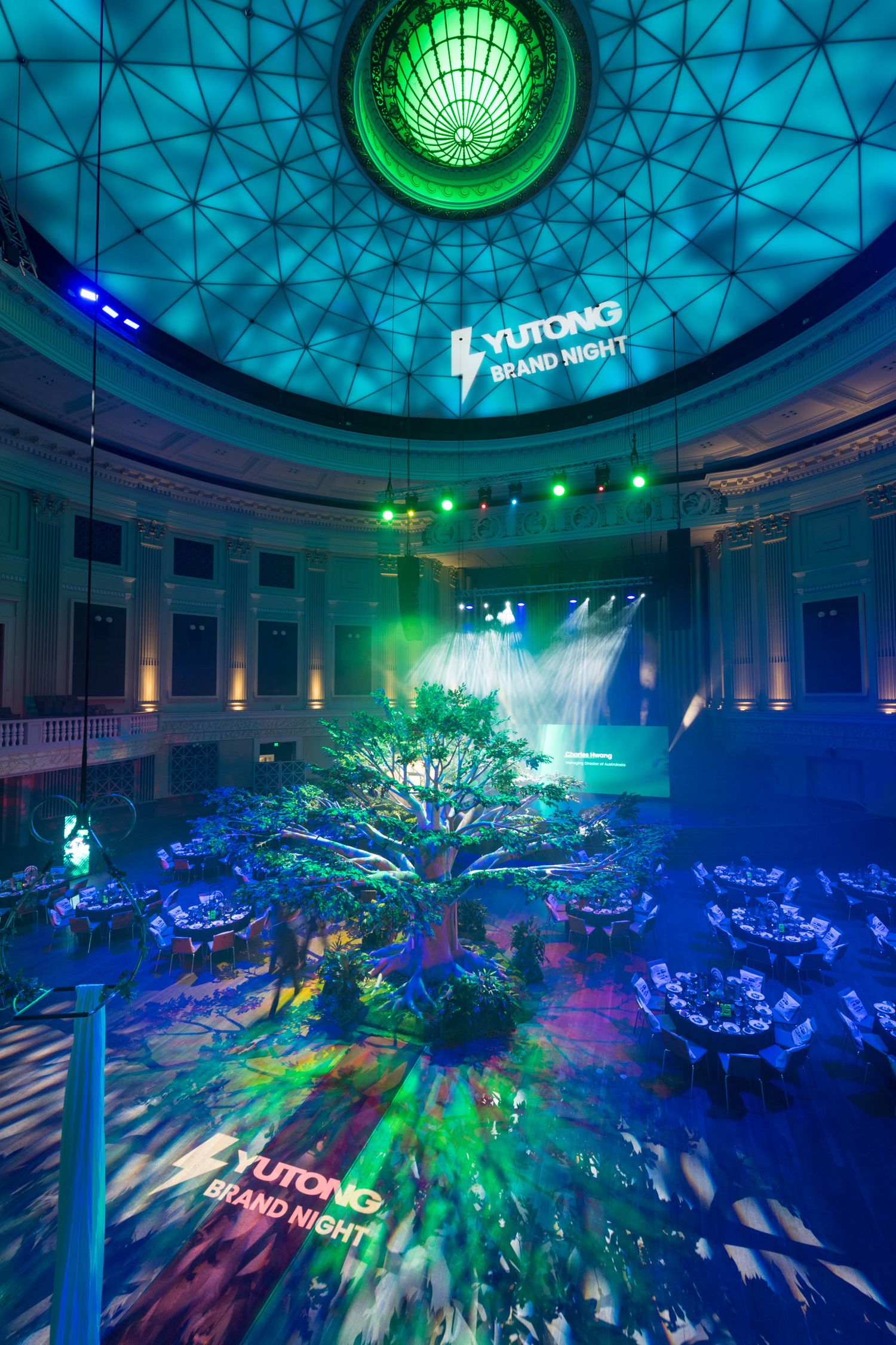 Stunning Yutong Brand Night event with a large decorative tree centerpiece under a domed ceiling with colorful lighting.