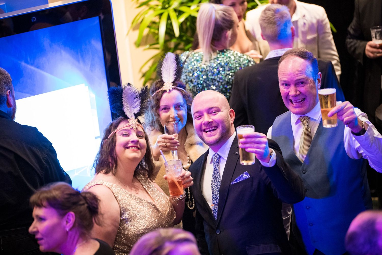 Cheerful guests raising glasses and smiling at lively corporate gala celebration.