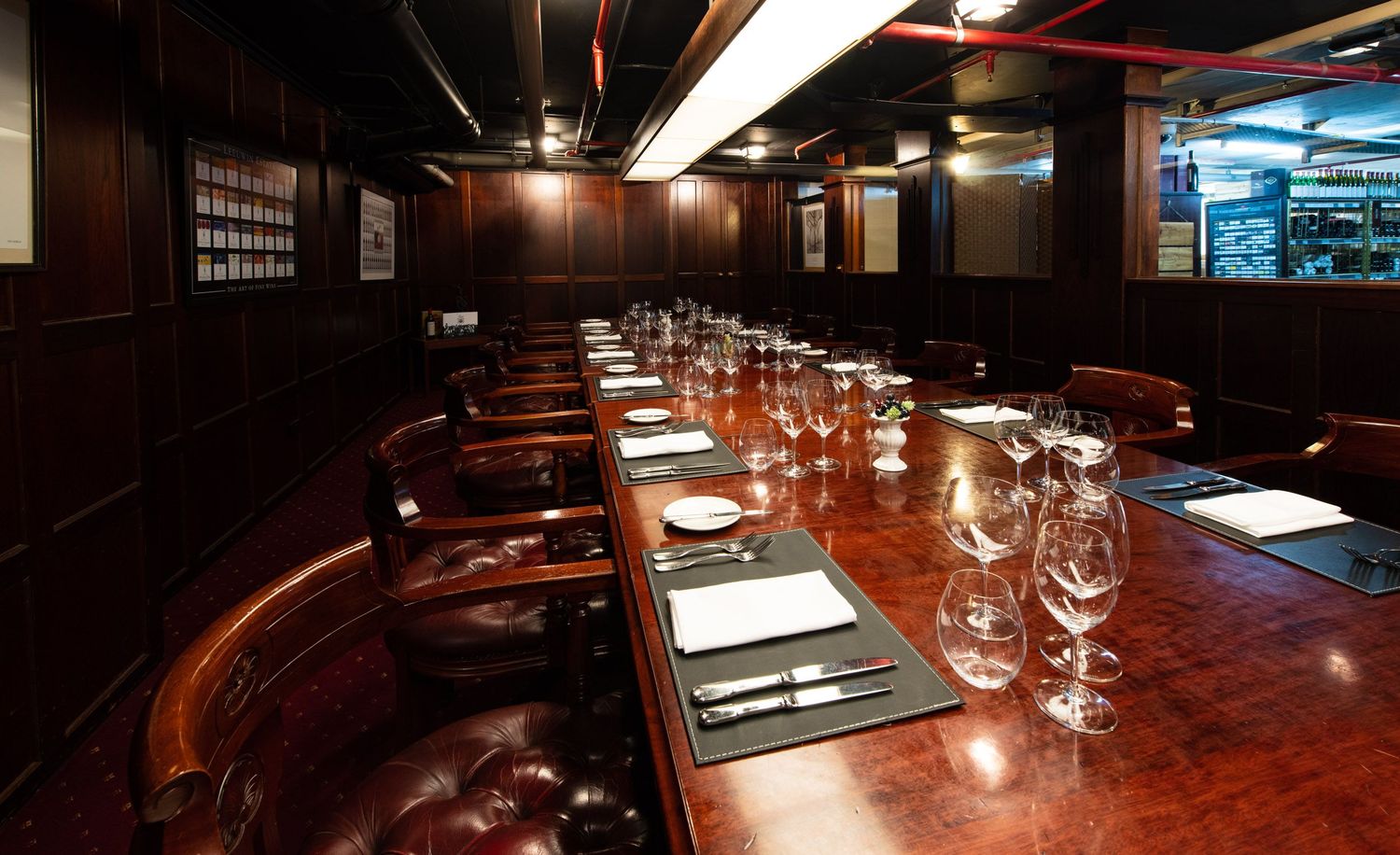Intimate dark wood private dining room with polished table set with wine glasses for an upscale dinner event.