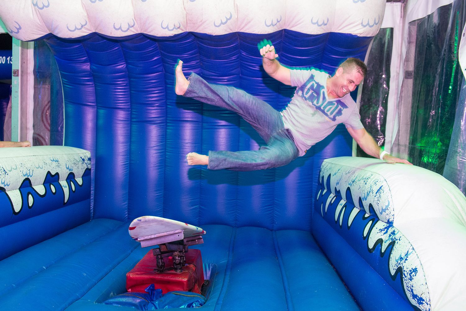 Man jumping energetically in an inflatable bouncy castle at an outdoor entertainment event.