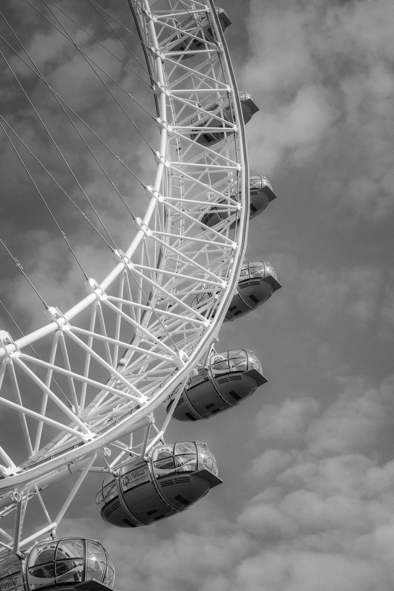 Black and white close-up of London Eye ferris wheel pods against a cloudy sky.